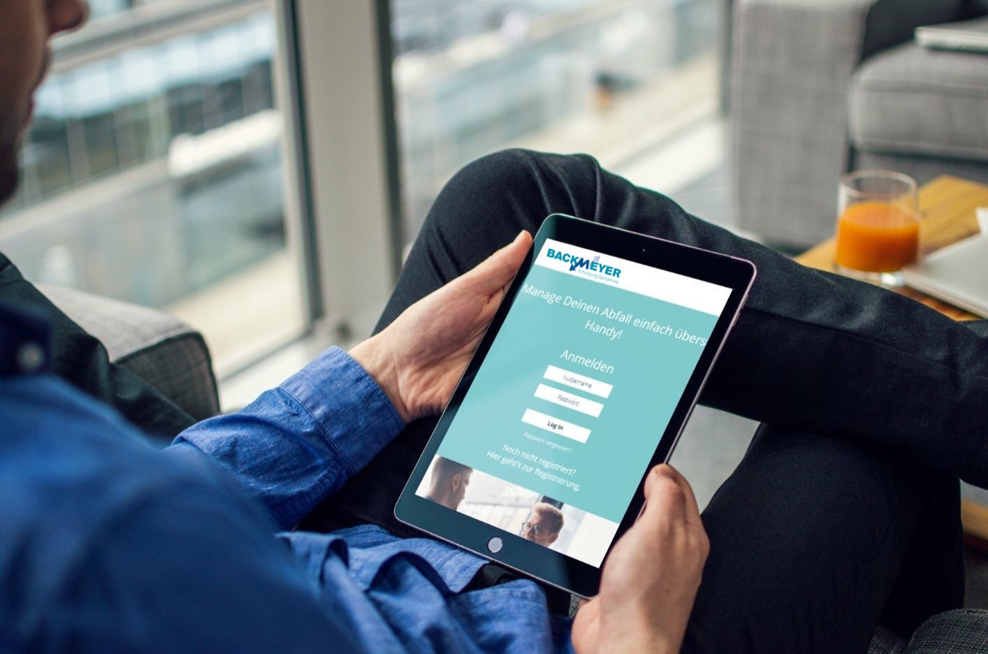 überschlagene Beine eines Mannes und seine Hände die ein Tablet halten